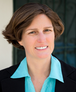 Middle age white female with brunette hair in a teal shirt and black blazer