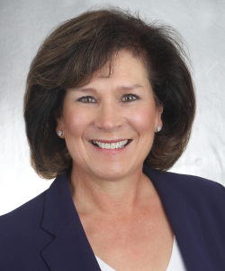 Middle age white female with brunette hair in a navy blue blazer