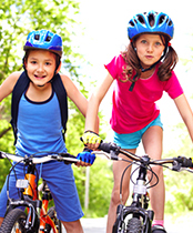 two children riding bikes next to one another with helmets